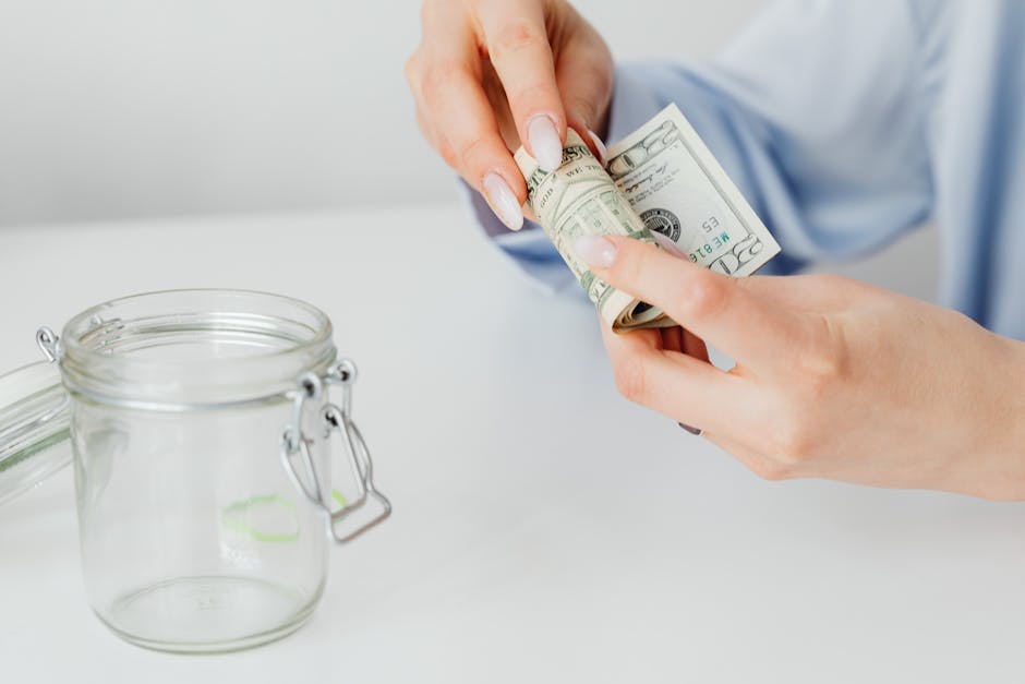 Woman rolling dollar bills beside a glass jar, symbolizing savings or financial planning.