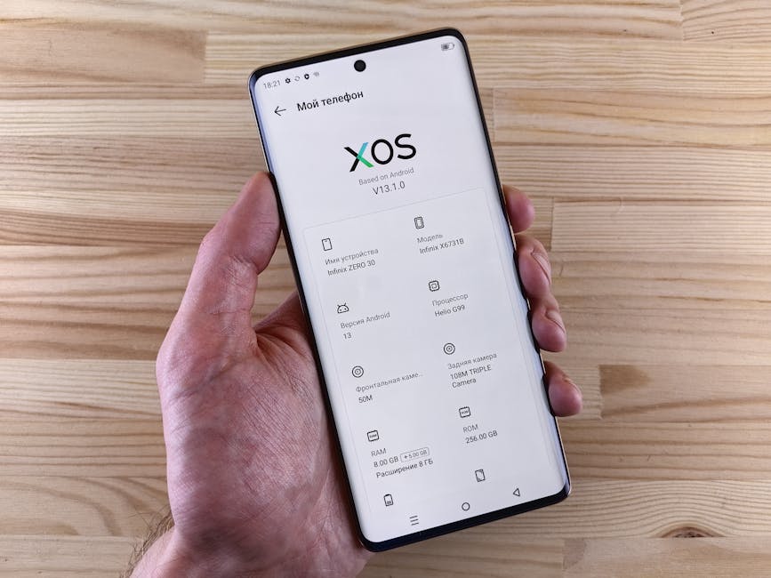 Close-up of a hand holding a smartphone displaying the XOS interface with specs.