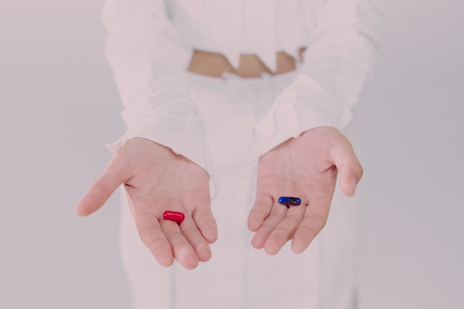 Close-up of hands holding red and blue pills, symbolizing a choice. Conceptual studio shot.